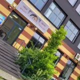 Elegancki budynek z oknami i drzwiami, z zielenią przed wejściem.